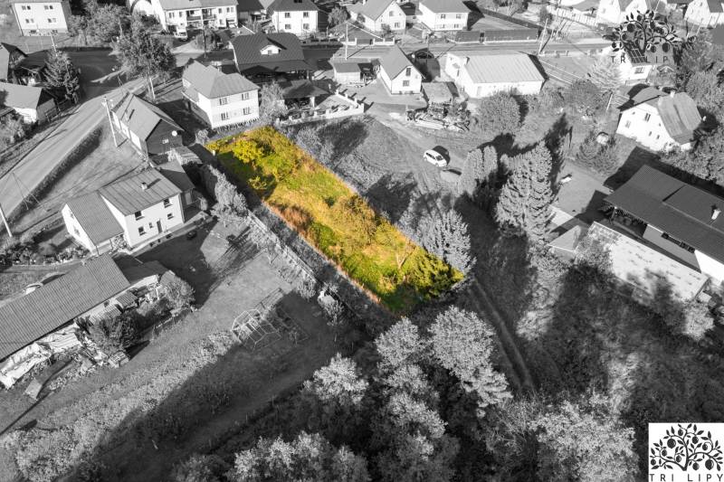 A plot for residential use in Turzovka, surrounded by houses, with grass cover and trees.