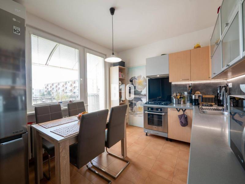 Kitchen in a 4-room apartment with a dining table, brown chairs, and a large window.