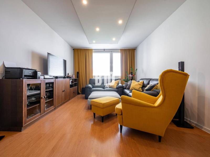 Living room in a 4-room apartment with a wood-patterned floor and yellow armchairs.