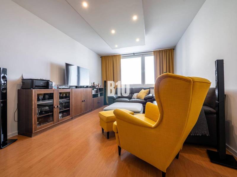 Living room in a 4-room apartment with a wooden decor floor, yellow armchair and sofa.