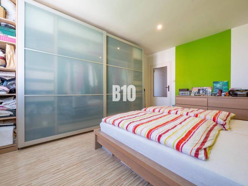A bedroom in a 4-room apartment with a wooden decor floor and a spacious wardrobe.