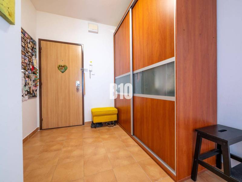 A hallway in a 4-room apartment with tiles and a built-in wardrobe.
