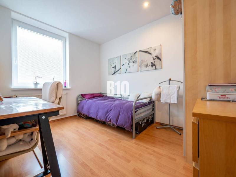 A bedroom in a 4-room apartment with a wood-patterned floor and a purple bedspread.
