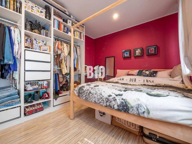 Bedroom with a bed, wood-patterned floor, and open wardrobe in a 4-room apartment.