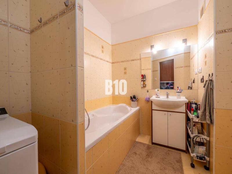 A bathroom with yellow tiles, a bathtub, a sink, and storage space in a 4-room apartment.