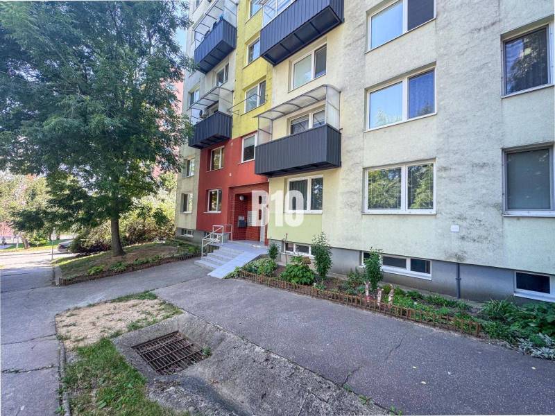 In Nitra, there is an apartment building with an interesting colorful facade near greenery.