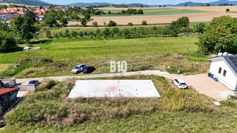 Plots - housing in Čeľadice with houses, cars, and natural landscape in the background.