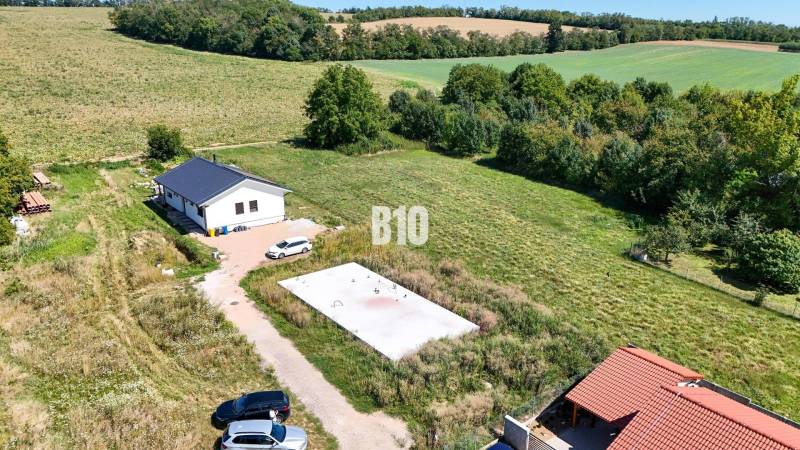 A plot of land for living in Čeľadice includes a house, greenery, and cars.