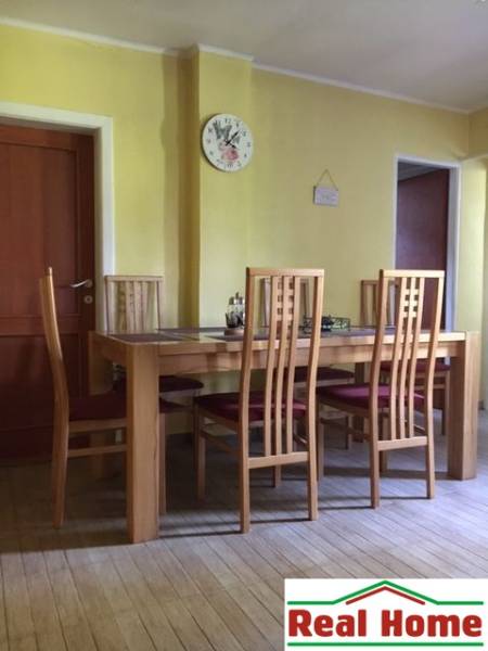 A dining room in a family house with chairs and a table on a floor with a wooden decor.