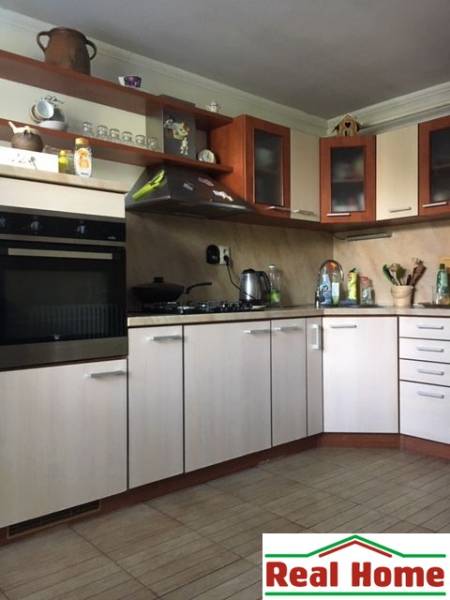 A kitchen in a family house with a wooden decor floor and light cabinets.