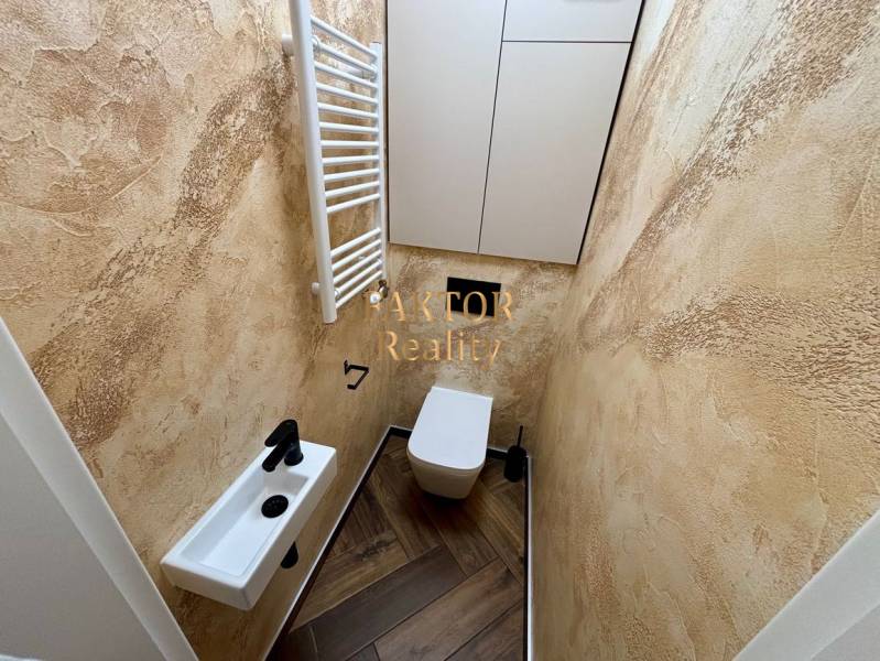 A bathroom in a two-room apartment with beige walls and a wooden decor floor.