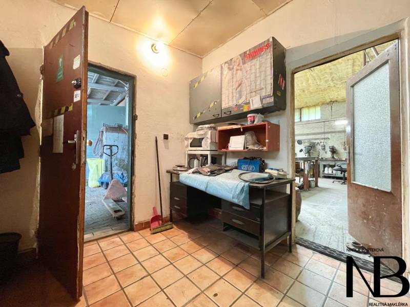 Interior of commercial premises with tiles, a workbench, and tools on shelves.
