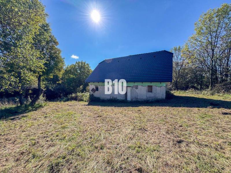 A cottage in Lackov surrounded by nature, with a blue roof, sunny day.