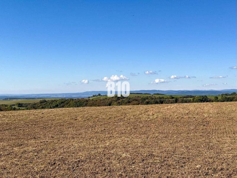 Flat landscape in Lackov with a view of distant hills and a blue sky.