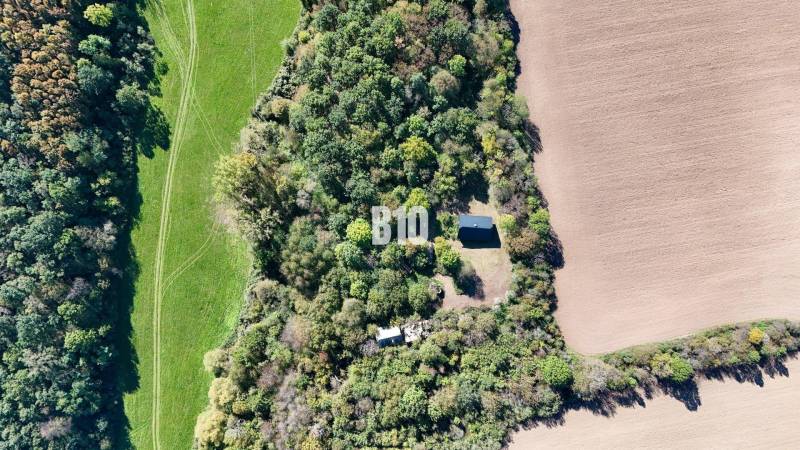 Aerial view of a cabin in Lackov surrounded by forest and fields.