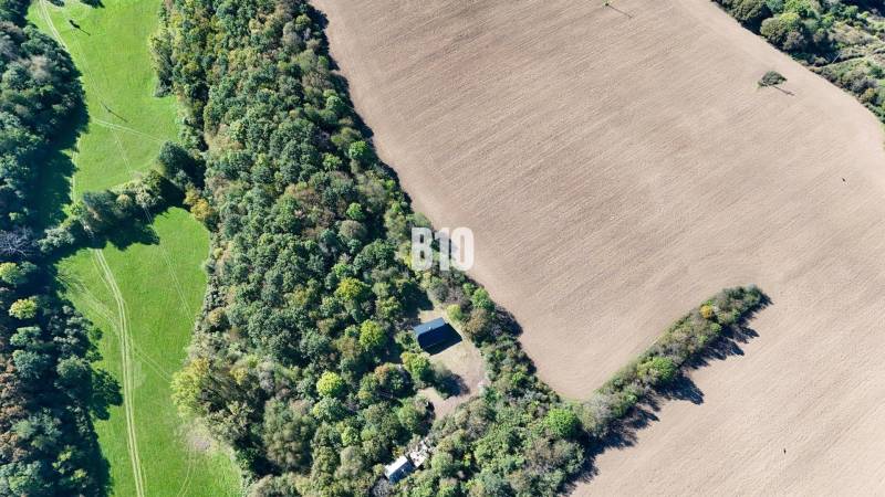 An aerial view of a cottage surrounded by forest and fields in Lackov.