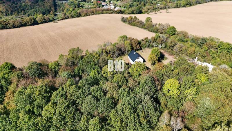 A cottage in Lackov surrounded by forest and fields, a peaceful rural landscape.