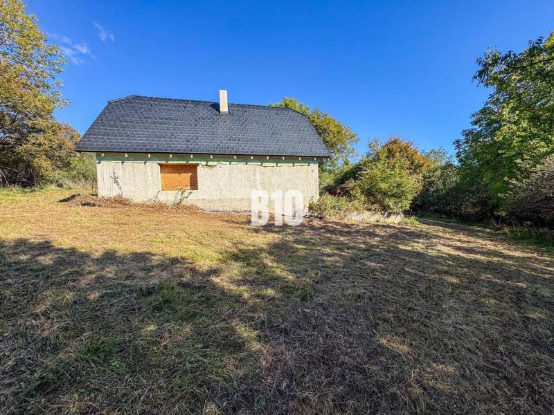 A cottage in Lackov surrounded by nature, depicted in a sunny environment.