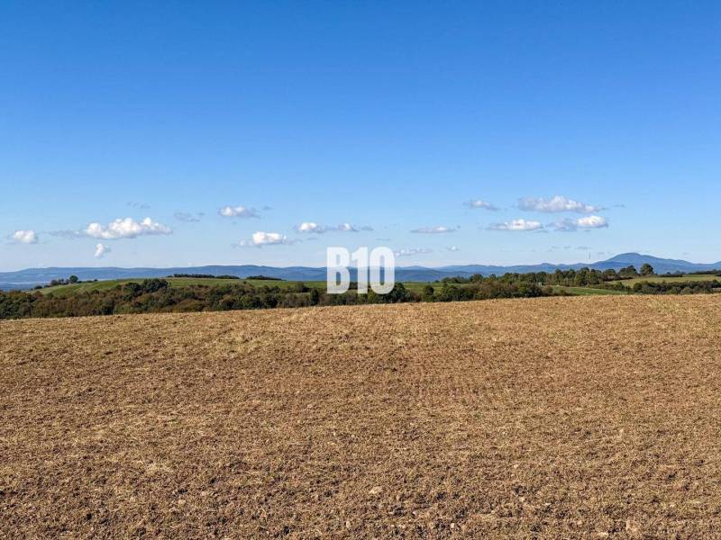 A view of a cultivated field in Lackov, with a view of the hills and a clear sky.