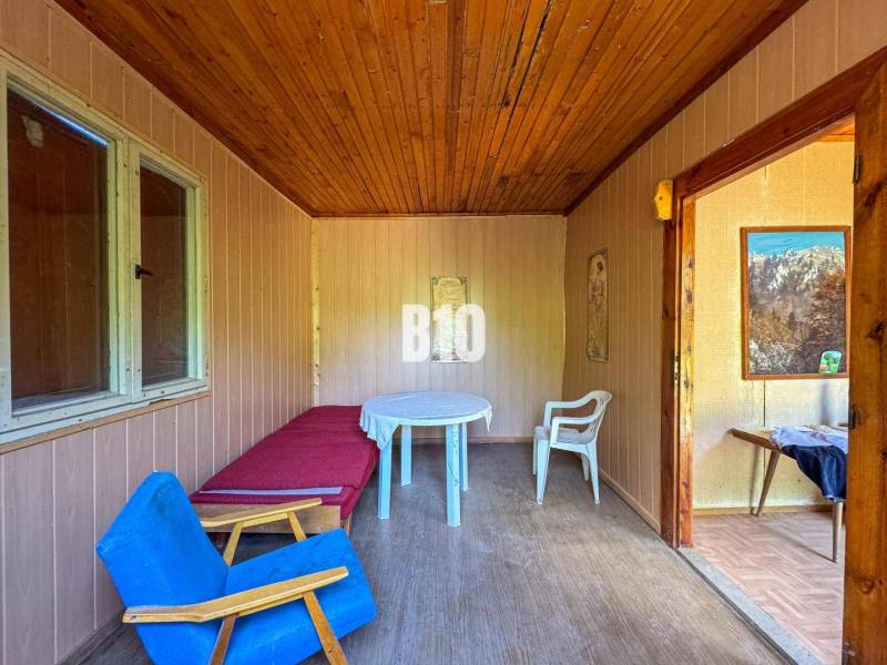 A room with a wooden ceiling, a chair, a table, and paintings, in the premises of a vineyard.