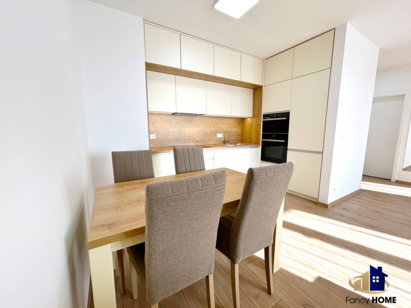 A kitchen in a two-room apartment with a dining table and chairs, flooring with a wooden decor.