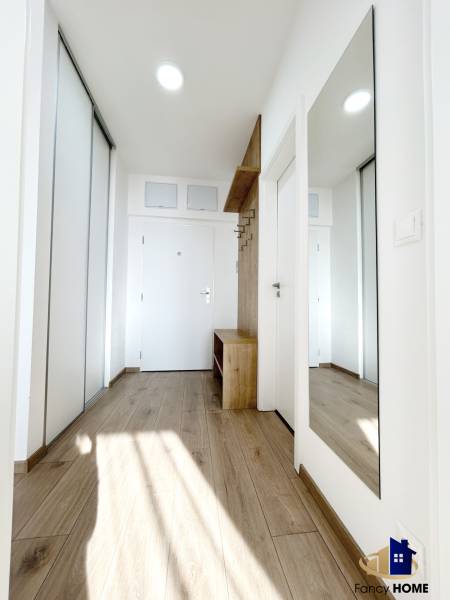 Entrance hall with a mirror and a wooden decor floor in a 2-room apartment.