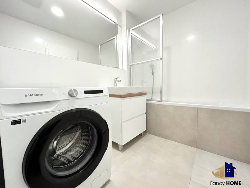 A bathroom in a 2-room apartment with a shower, bathtub, and washing machine.