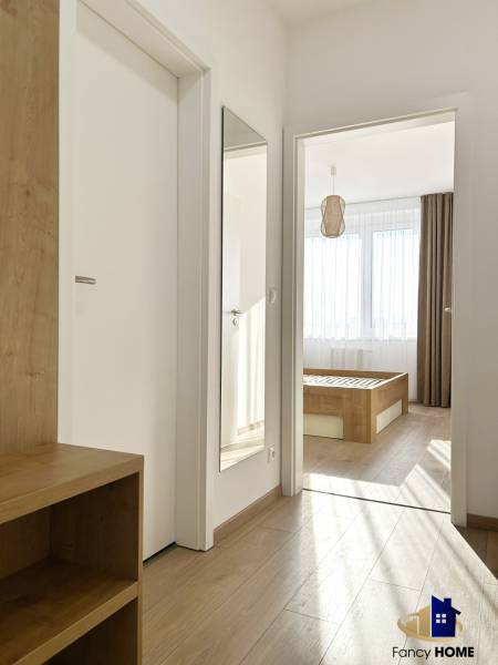 A hallway in a 2-room apartment with a wooden decor floor and a mirror on the wall.