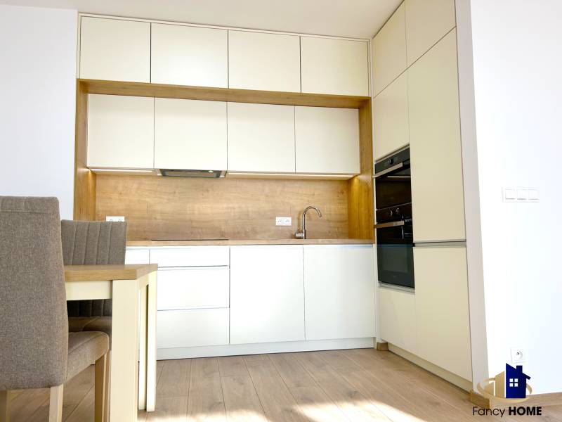 A kitchen in a 2-room apartment with white cabinets and a floor with a wood design.