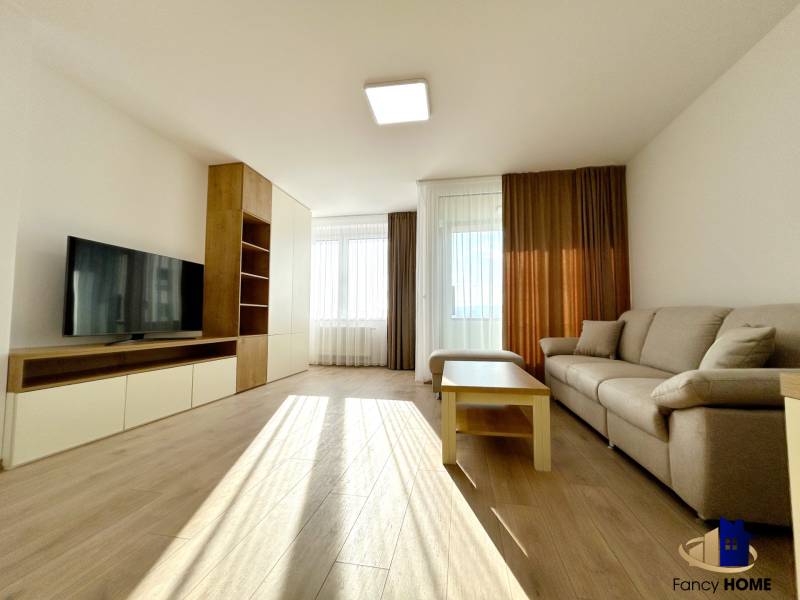 Living room with a sofa, television, table, and wooden decor flooring in a 2-room apartment.