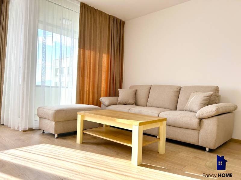 Living room in a two-room apartment with a sofa, table, and floor with a wooden decor.