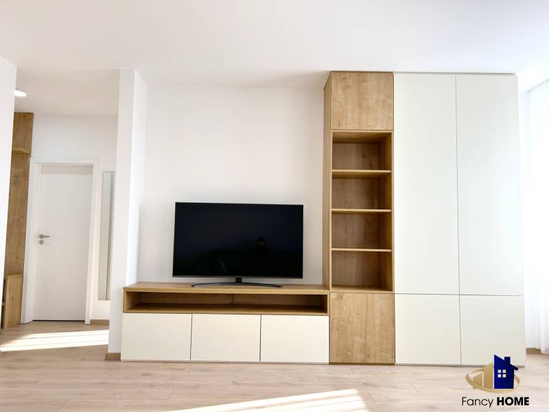 Living room in a 2-room apartment with a TV and furniture with a wooden decor.