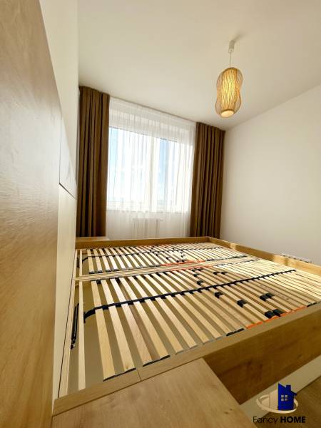 Bedroom with a bed and a lamp in a 2-room apartment with a wood-patterned floor.