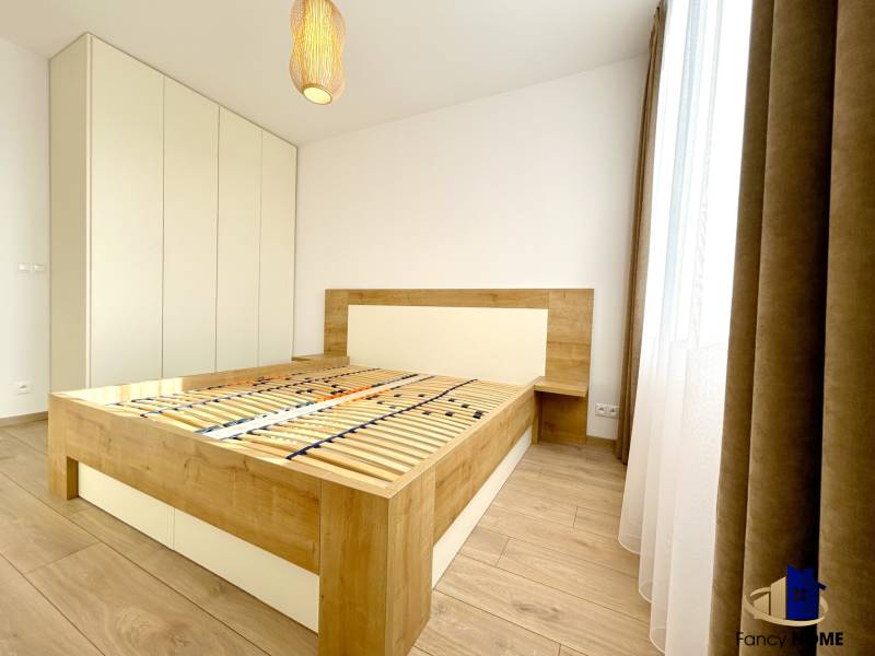 A bedroom with a bed frame and a wooden decor floor in a two-room apartment.