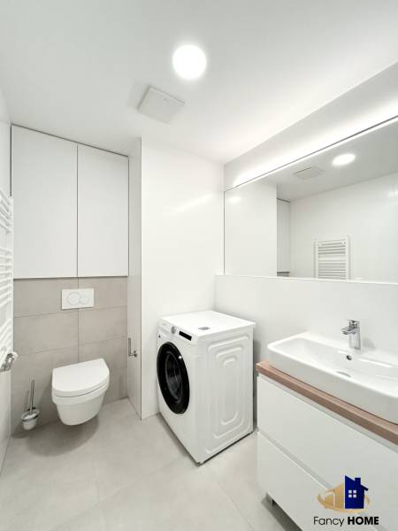 Bathroom with a shower, sink, and washing machine in a 2-room apartment.