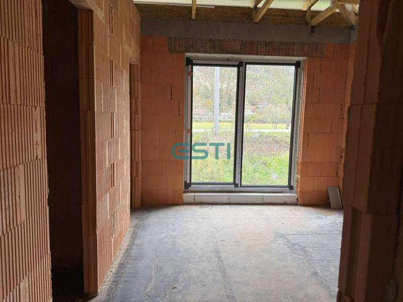 An incomplete structure with brick walls and a large window in a family house.