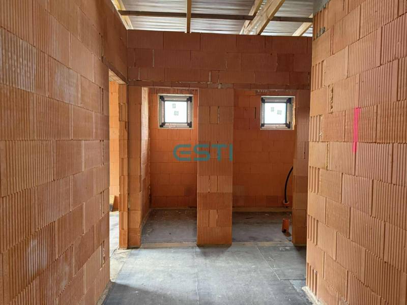Interior of a family house with brick partitions, two small windows, concrete floor.