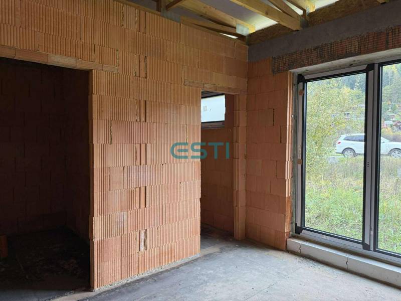 Unfinished interior in a family house with a large window and brick walls.