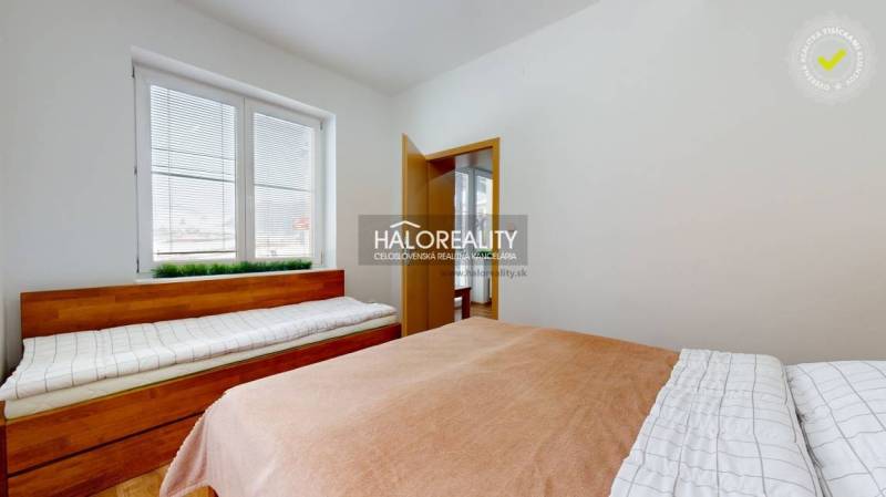 A bedroom in a three-room apartment with two beds and a window with blinds.