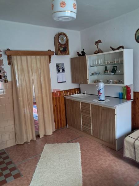 Interior of a family house with a simple kitchen, wooden decor flooring, and curtains.