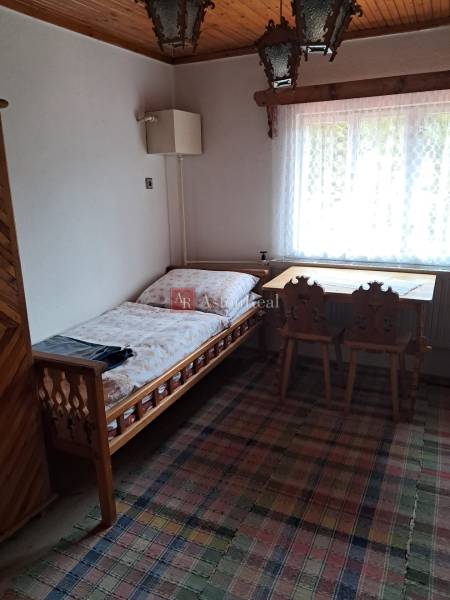 A room in a family house with a bed, a window, a table, and chairs.