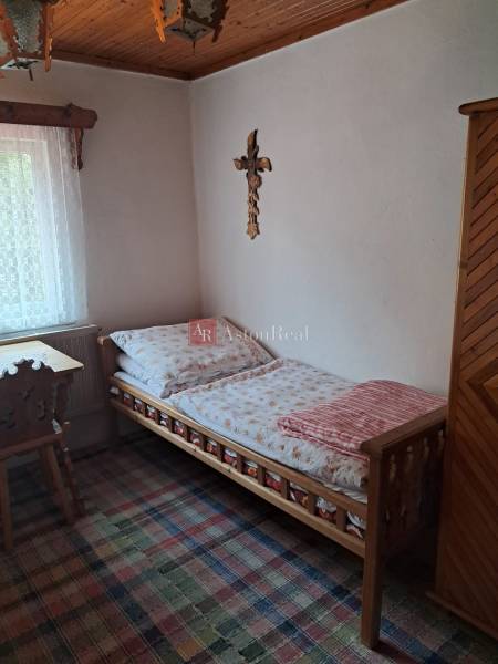 A simple room in a family house with wooden furniture, a carpet, and a cross on the wall.