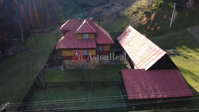 A family house in Zázrivá surrounded by nature, with a red roof and a wooden barn.