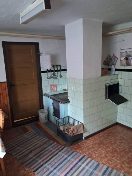 A kitchen in a family house with an antique stove, tiles, and a floor with a wooden decor.
