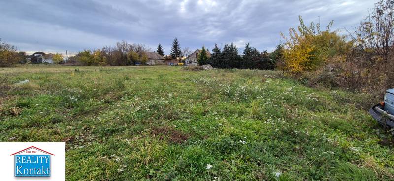 Residential plots in Tvrdošovce, overgrown meadow, rural houses in the background.