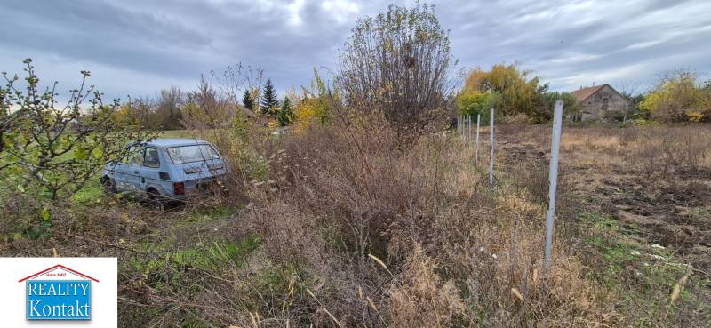 A plot for residential use in Tvrdošovce with an abandoned car and overgrown terrain.
