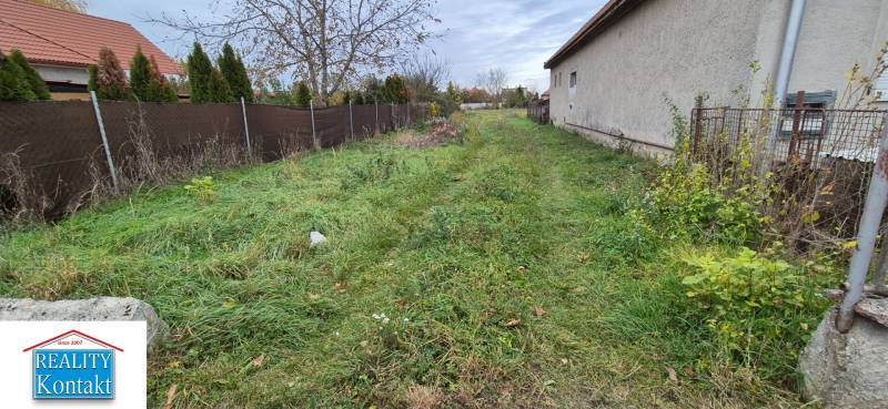 A grassy plot in Tvrdošovce designated for residential use, bordered by a fence and a building.