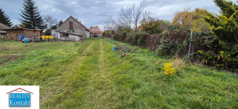 A garden with a lawn and older buildings in Tvrdošovce suitable for residential plots.