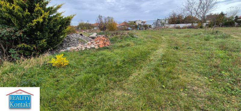 Green residential land in Tvrdošovce with piles of debris and dense vegetation.