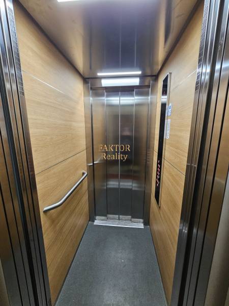 The interior of the elevator with wood decor panels and stainless steel elements.
